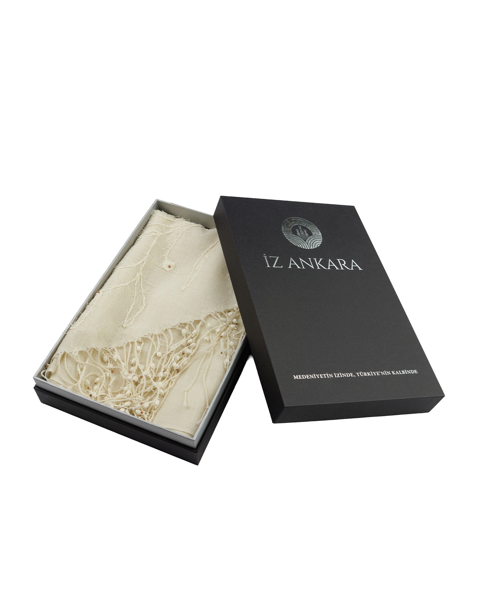 Black box with 'IZ ANKARA' branding containing a piece of beige fabric on a white background