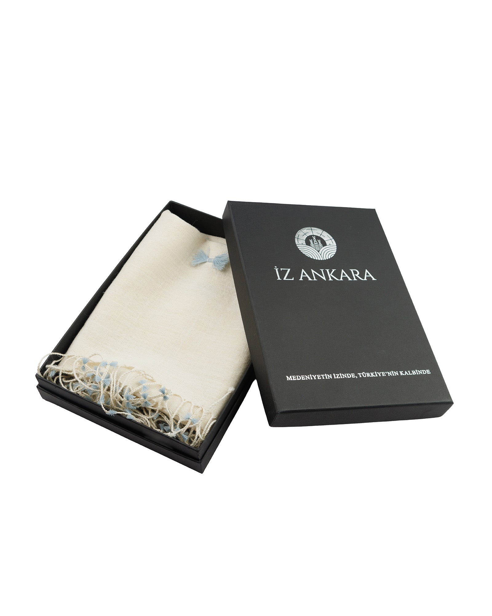 Black box with 'IZ ANKARA' branding containing a white scarf and decorative item on a white background.
